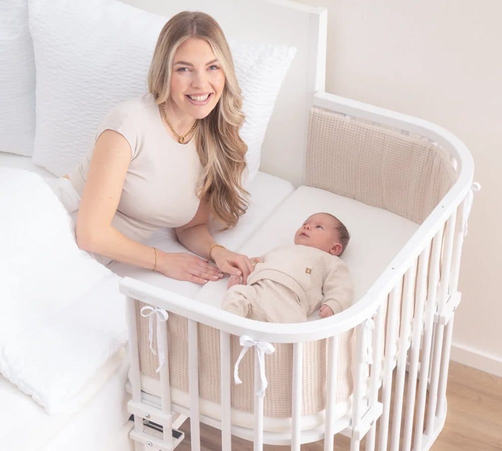 Madre en su cama junto a su bebé, en la cuna colecho babybay acoplada